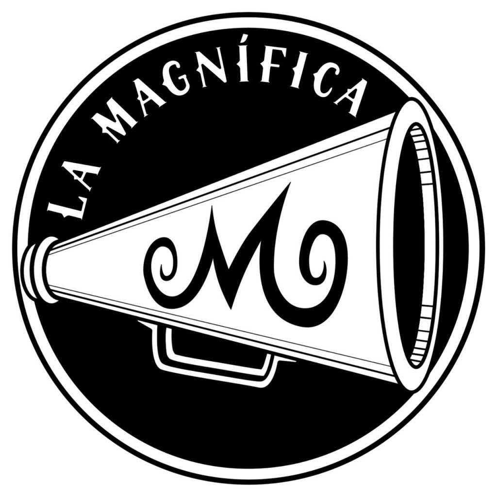 Logo circular con fondo negro donde se ve escrito siguiendo la curva del círculo La Magnífica. En el centro del círculo hay un megáfono blanco con una M negra en medio.