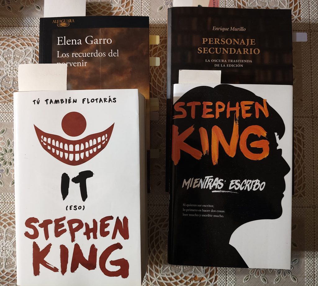 Foto de los libros Los recuerdos del Porvenir, Personaje Secundario, It y Mientras Escribo. Todos ellos con marcapáginas demostrando que están empezados y pegatinas de colores que salen por el lateral indicando pasajes de interés